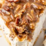 Slice of cheesecake pie with pecan pie topping on it.