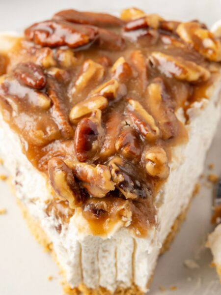 Slice of cheesecake pie with pecan pie topping on it.