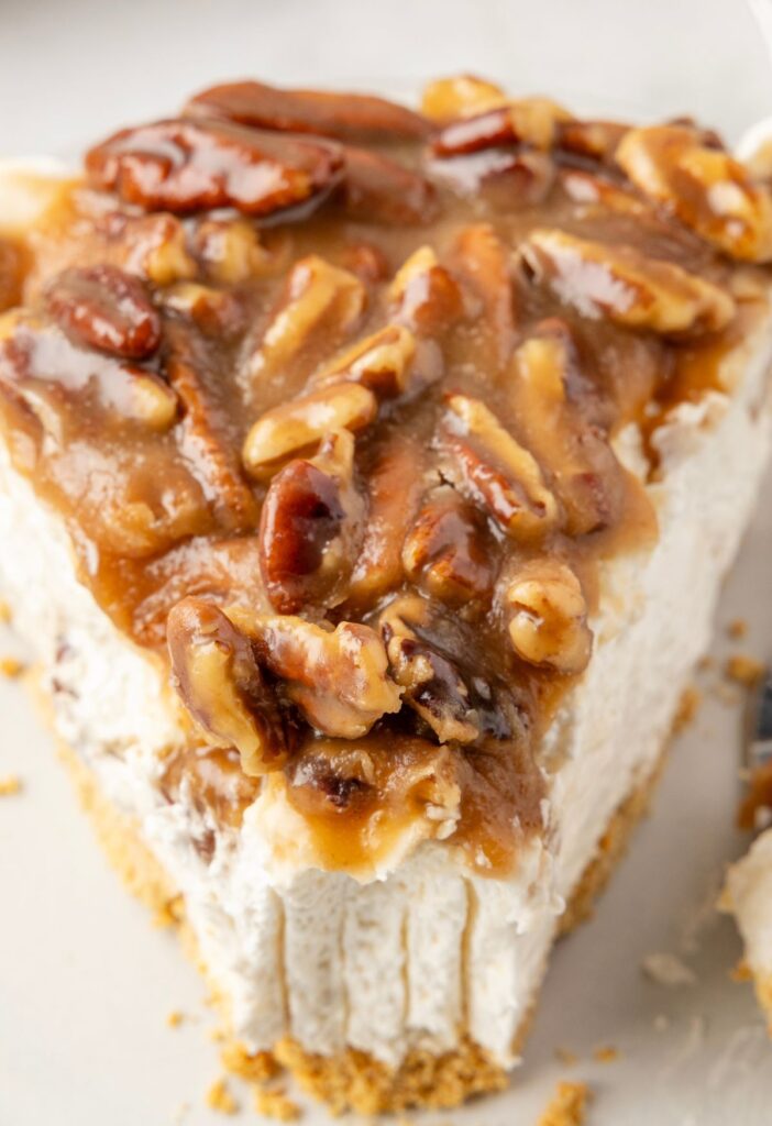 Slice of cheesecake pie with pecan pie topping on it. 