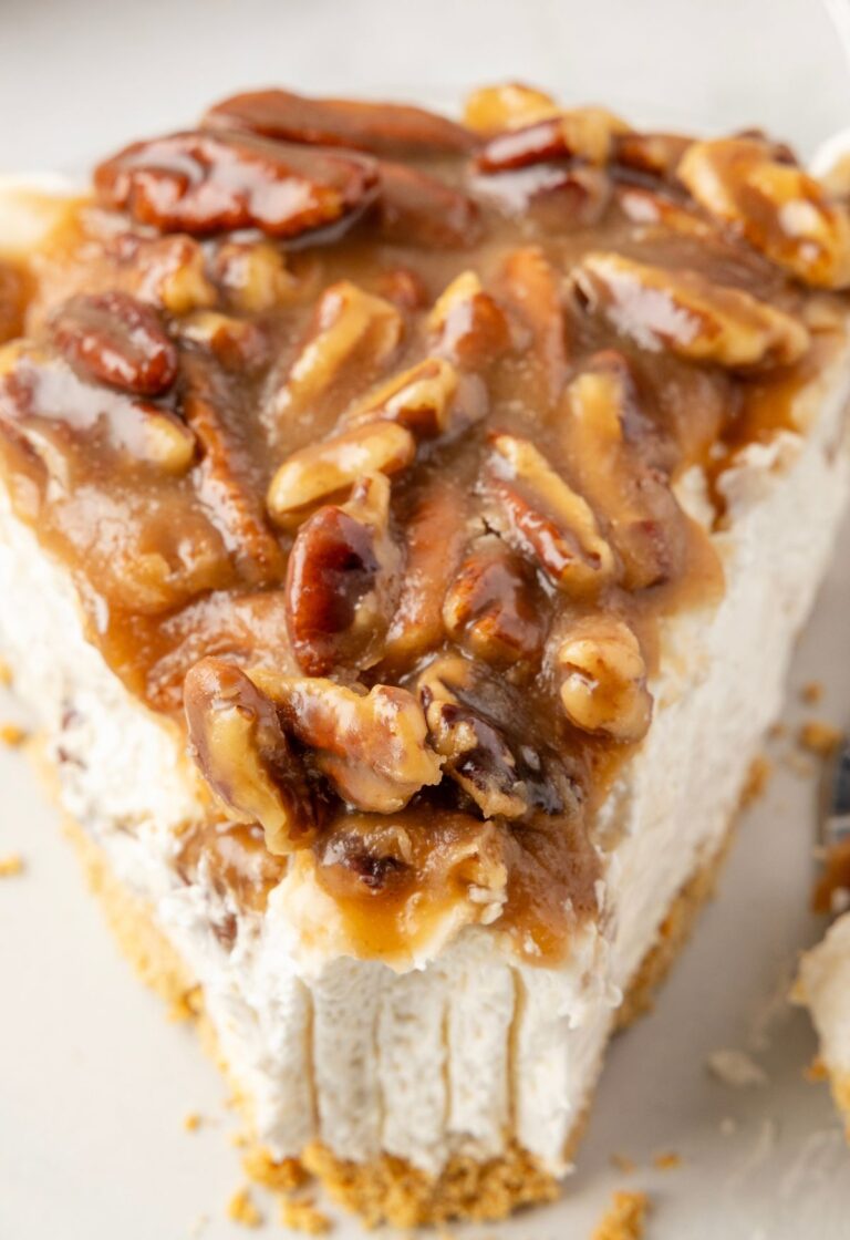 Slice of cheesecake pie with pecan pie topping on it.