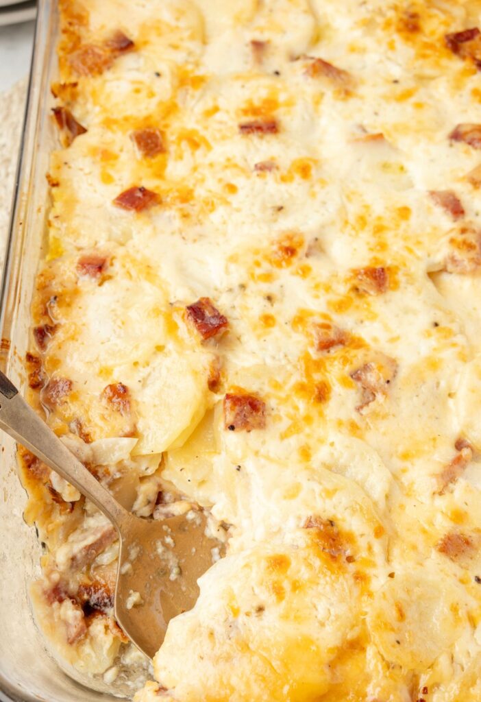 The oven baked potatoes with a spoon inside the potato casserole dish. 