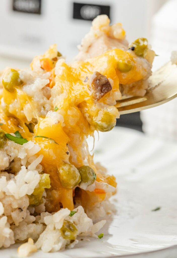 A serving of cheesy rice and chicken up close on a fork. 