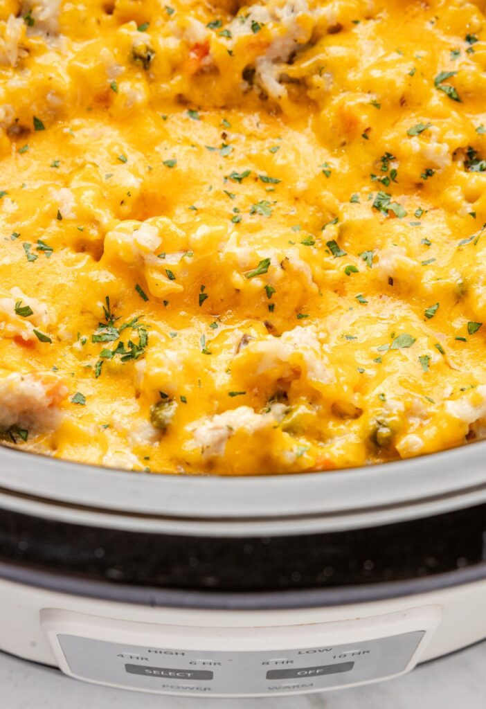 Inside view of the slow cooker with melted cheese over the chicken and rice casserole. 