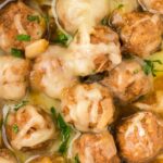 Close up of the meatballs with sauce and shredded gruyere cheese on top