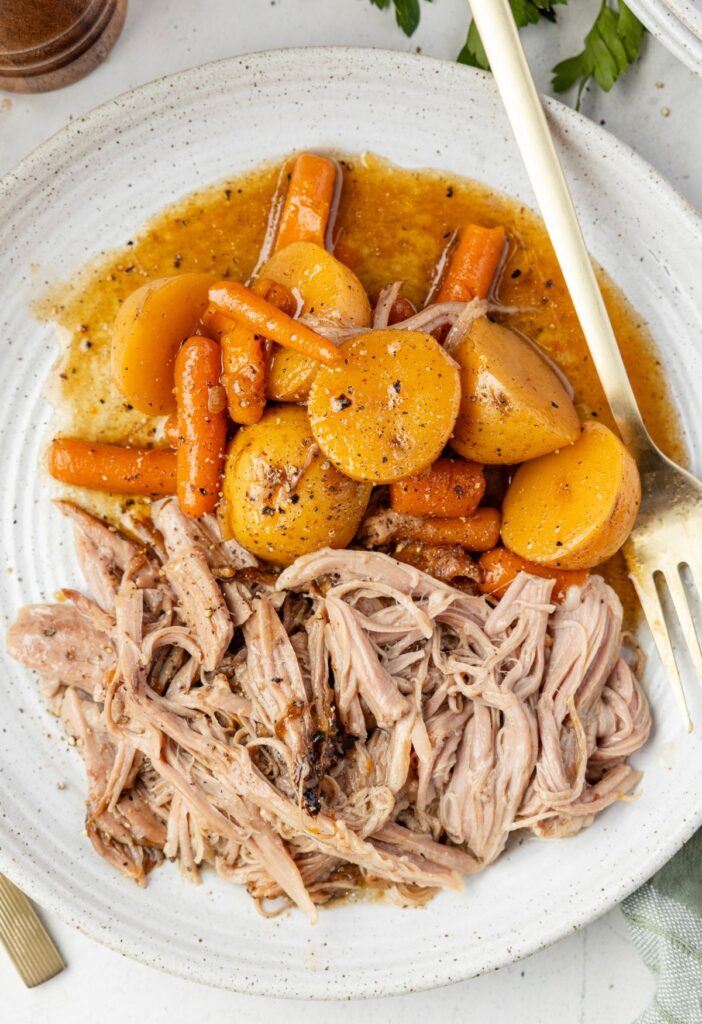 A white plate with a serving of the pork roast and vegetables. 
