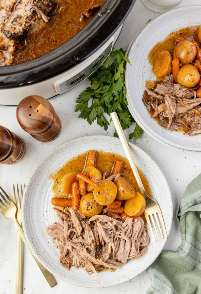 Slow cooker with the roast in it and a serving plate with some on it. 