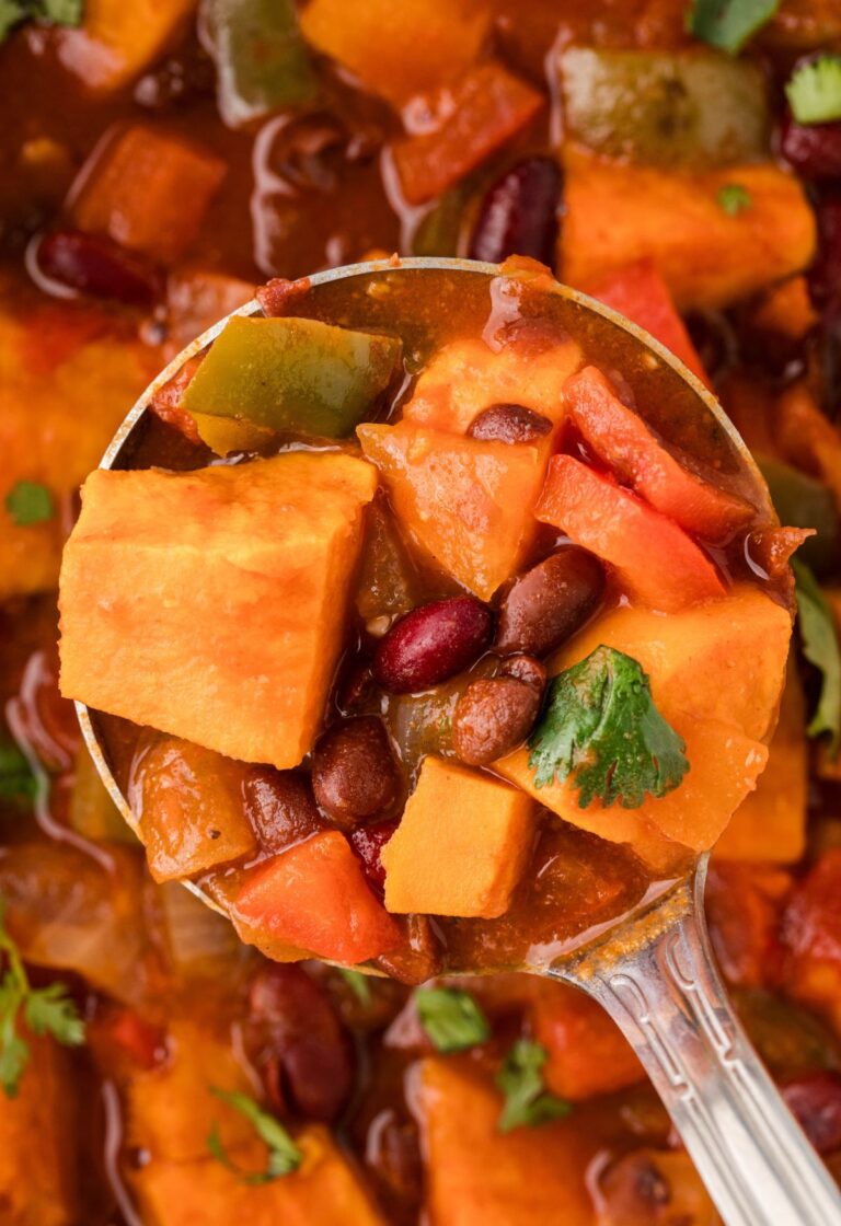 A soup ladle with some chunky chili in it