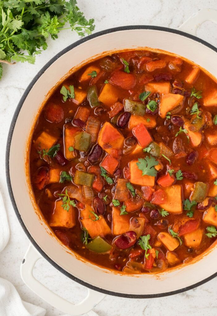 Pot of chunky vegetable chili with cilantro to the side. 