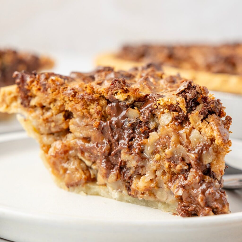 Side view of a piece of Texas trash pie on a white plate. 