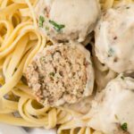 Serving of the meatballs with Alfredo Sauce with one meatball cut in half.