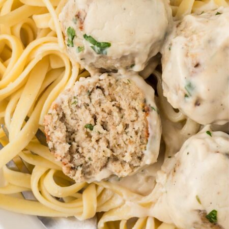 Serving of the meatballs with Alfredo Sauce with one meatball cut in half.