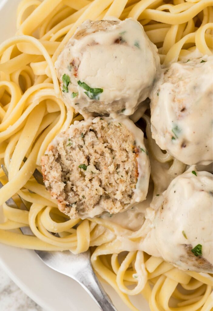 Serving of the meatballs with Alfredo Sauce with one meatball cut in half. 