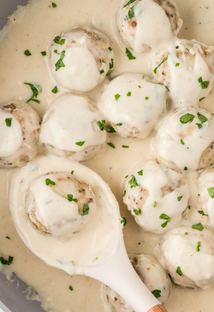 Skillet pan of Alfredo sauce with chicken meatballs in it. 
