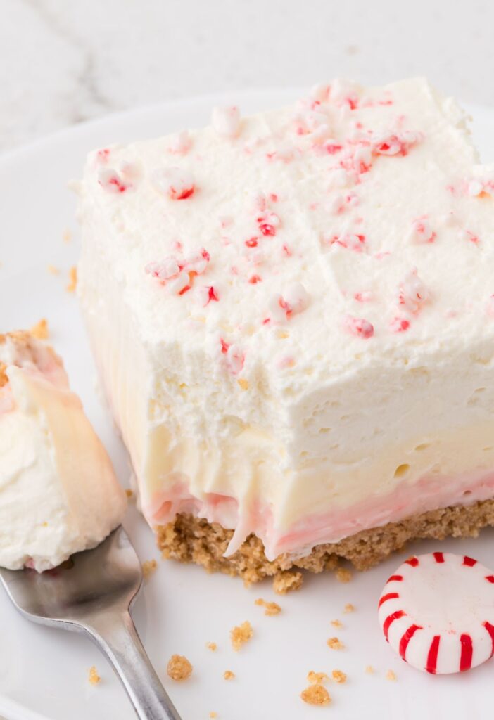 A square of the lush dessert with a fork and a peppermint candy. 