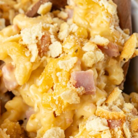 Close up of the ham casserole with cheese sauce on a wooden serving spoon.