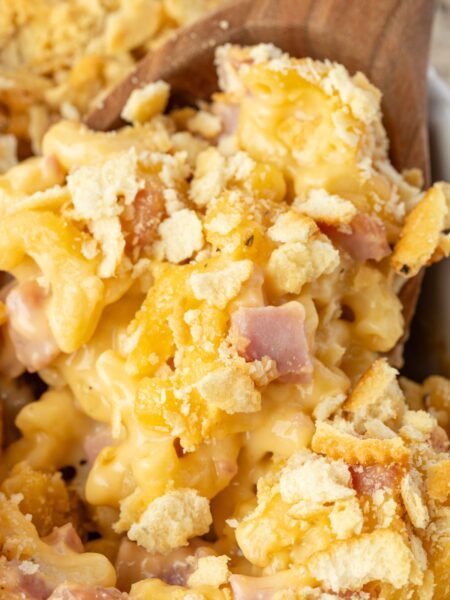 Close up of the ham casserole with cheese sauce on a wooden serving spoon.