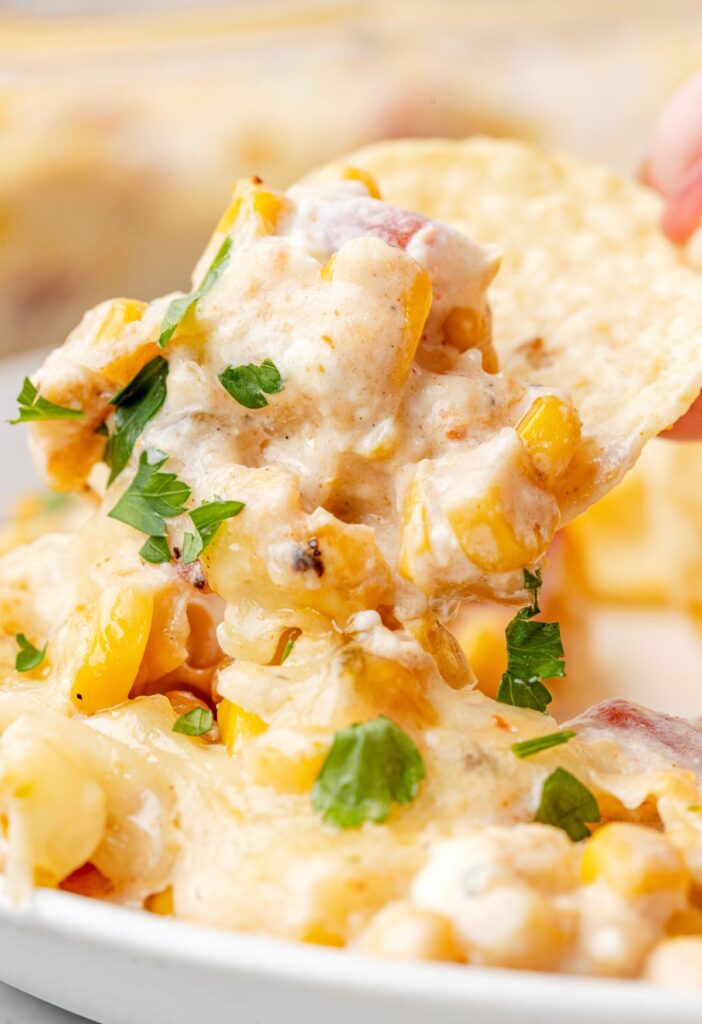 Tortilla chip with the cheesy creamy hot corn dip on it.