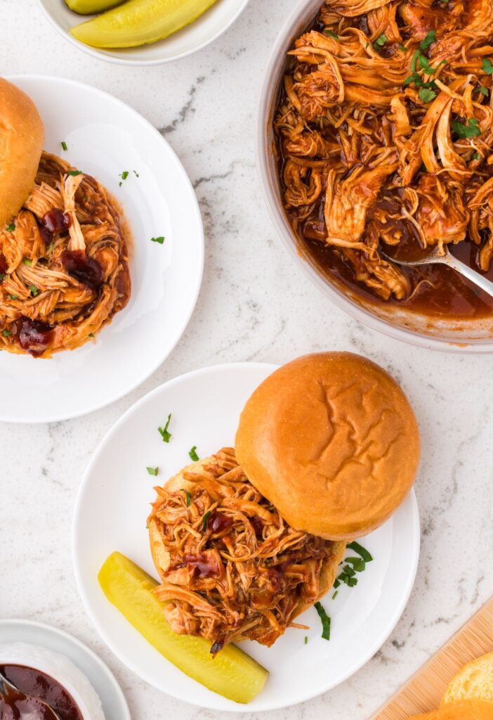 Overhead pic of the pressure cooker with the bbq chicken in it, and a serving plate with a sandwich. 