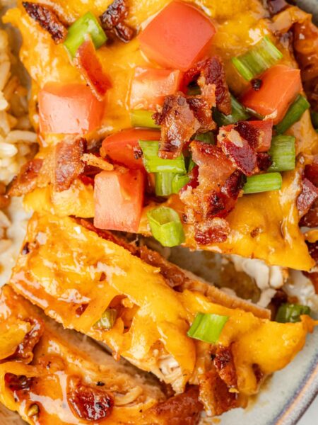 Chicken breast with bbq sauce, cheese, and bacon cut into slices.