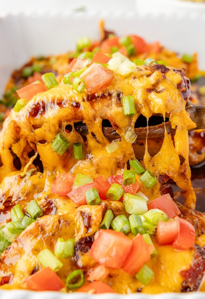Pan of Monterey chicken with a serving spoon lifting one out. 