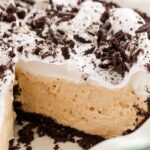 Pie plate with the peanut butter pie in it and Oreo crust, a piece cut out so you can see the center.