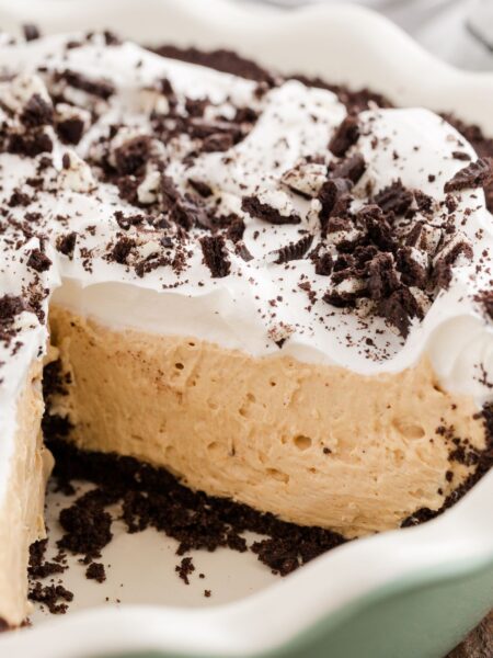 Pie plate with the peanut butter pie in it and Oreo crust, a piece cut out so you can see the center.