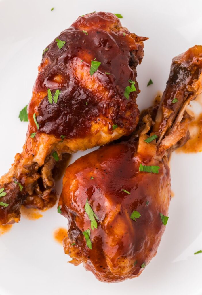 two chicken drumsticks on a white plate