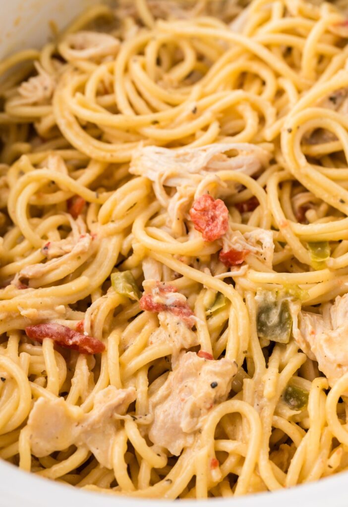 Close up of the creamy cheesy chicken spaghetti inside a white slow cooker.
