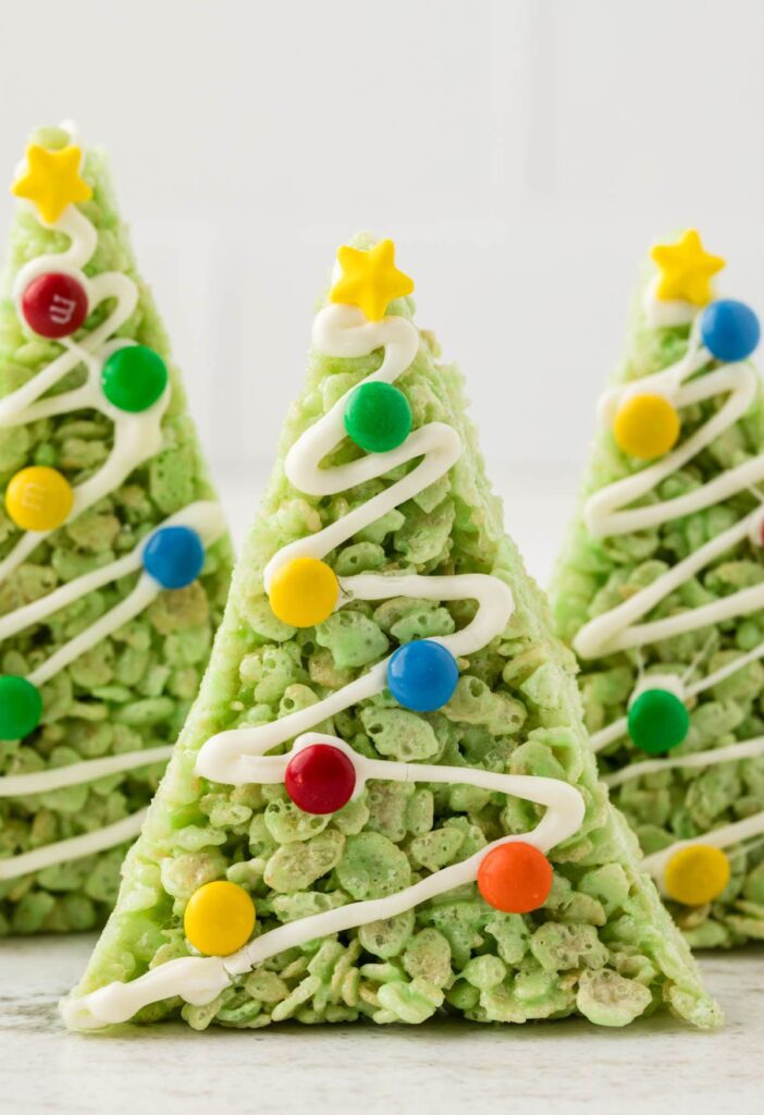 A tree Rice Krispie treat decorated with candy and white chocolate, standing up to look like a tree.