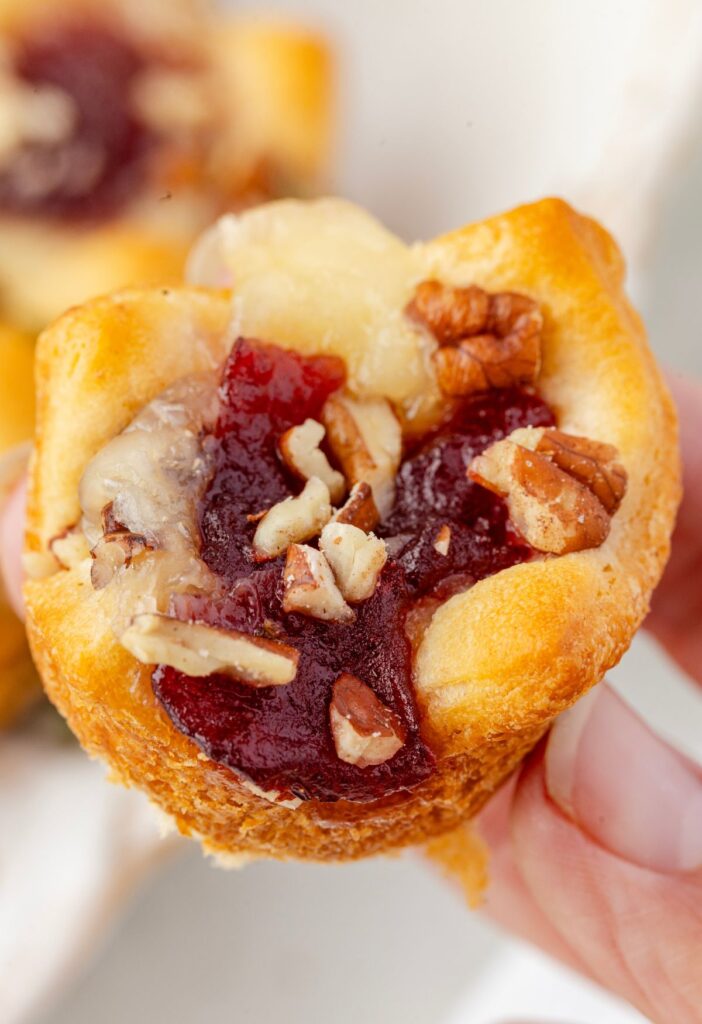 A hand holding cranberry brie bite
