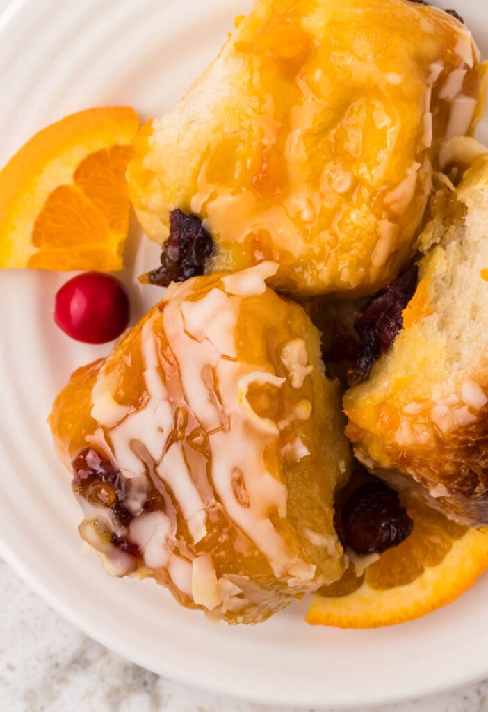 A serving of monkey bread with cranberries and orange on a white serving plate. 