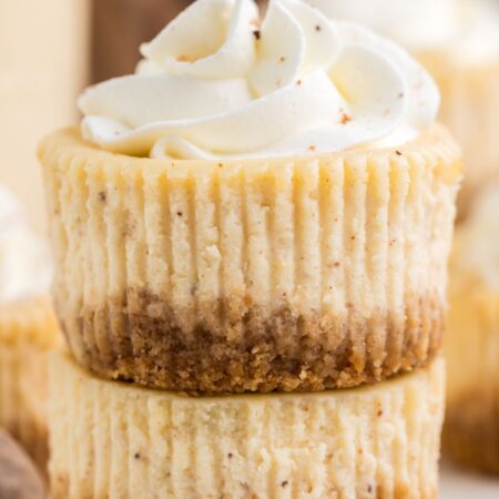 Stack of two mini cheesecakes with whipped cream on top.