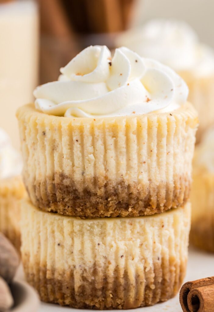 Stack of two mini cheesecakes with whipped cream on top.