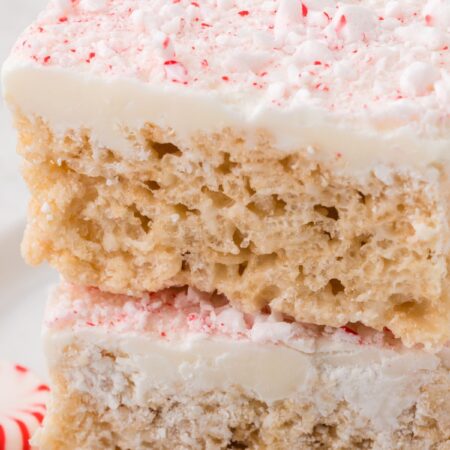 Stack of two squares of peppermint Rice Krispie treats with peppermint candy next to it.