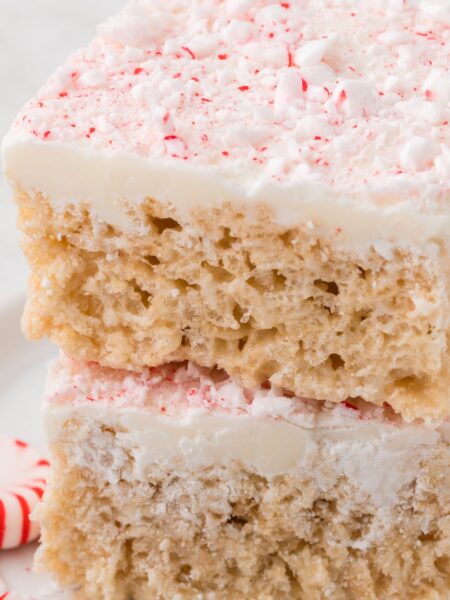 Stack of two squares of peppermint Rice Krispie treats with peppermint candy next to it.