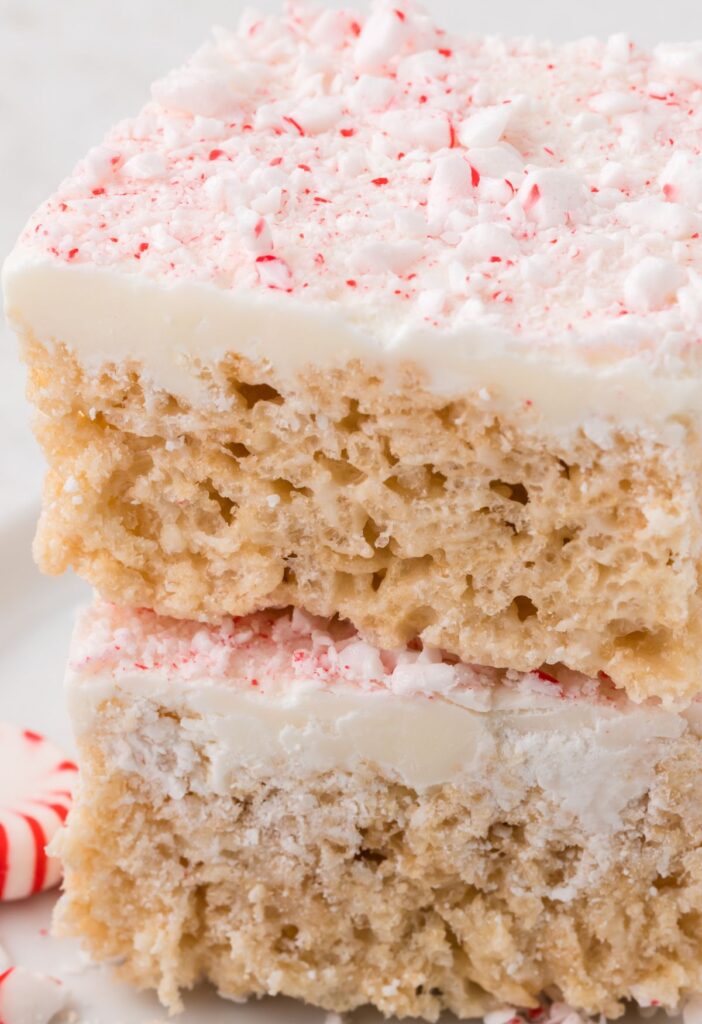 Stack of two squares of peppermint Rice Krispie treats with peppermint candy next to it. 