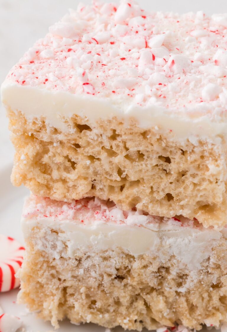 Stack of two squares of peppermint Rice Krispie treats with peppermint candy next to it.