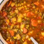Soup pot of vegetable soup with a soup ladle in the soup.