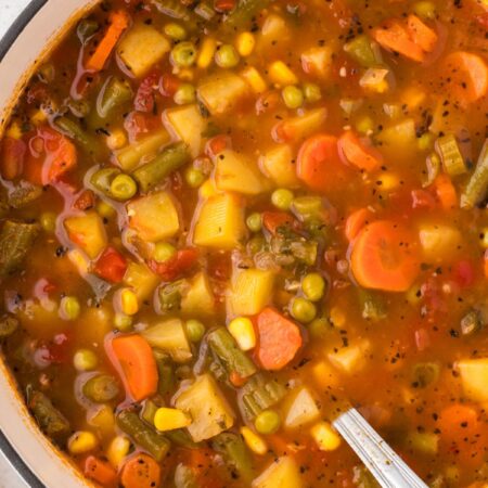 Soup pot of vegetable soup with a soup ladle in the soup.