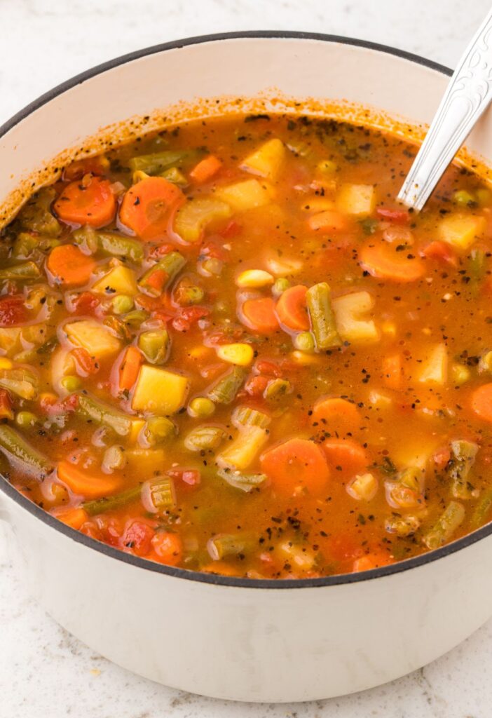 White pot of soup with a soup ladle in it.