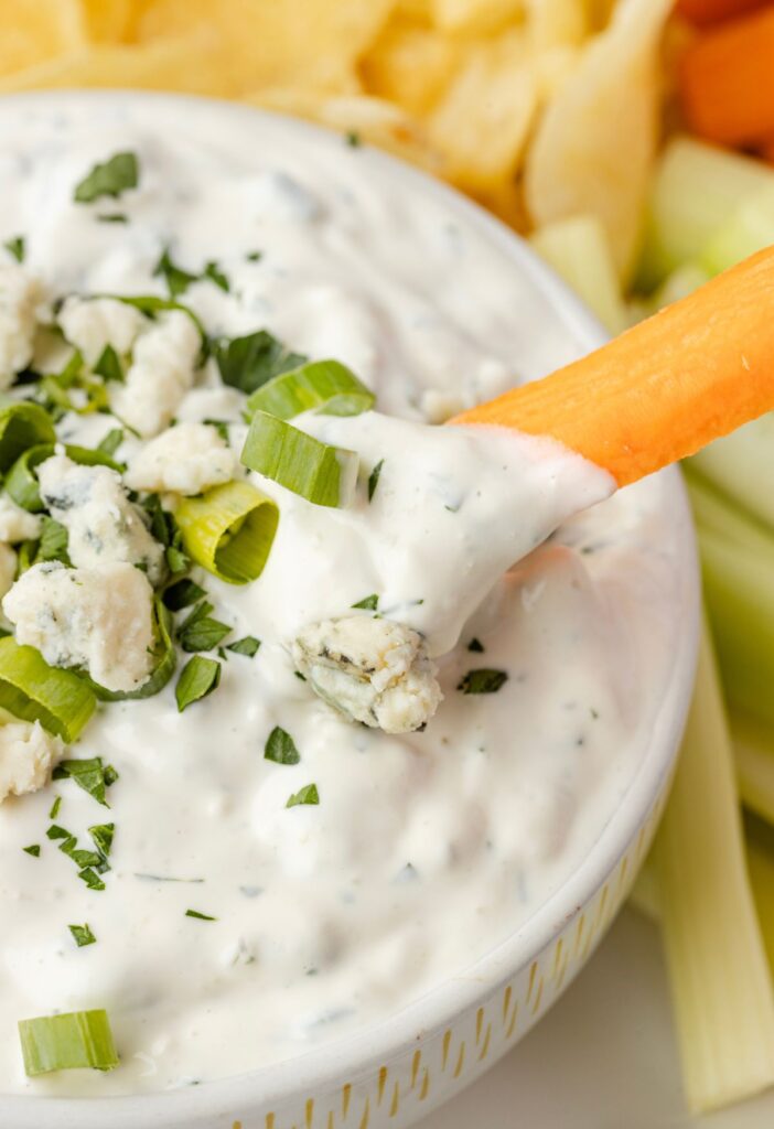 A carrot being dipped in the blue cheese dip