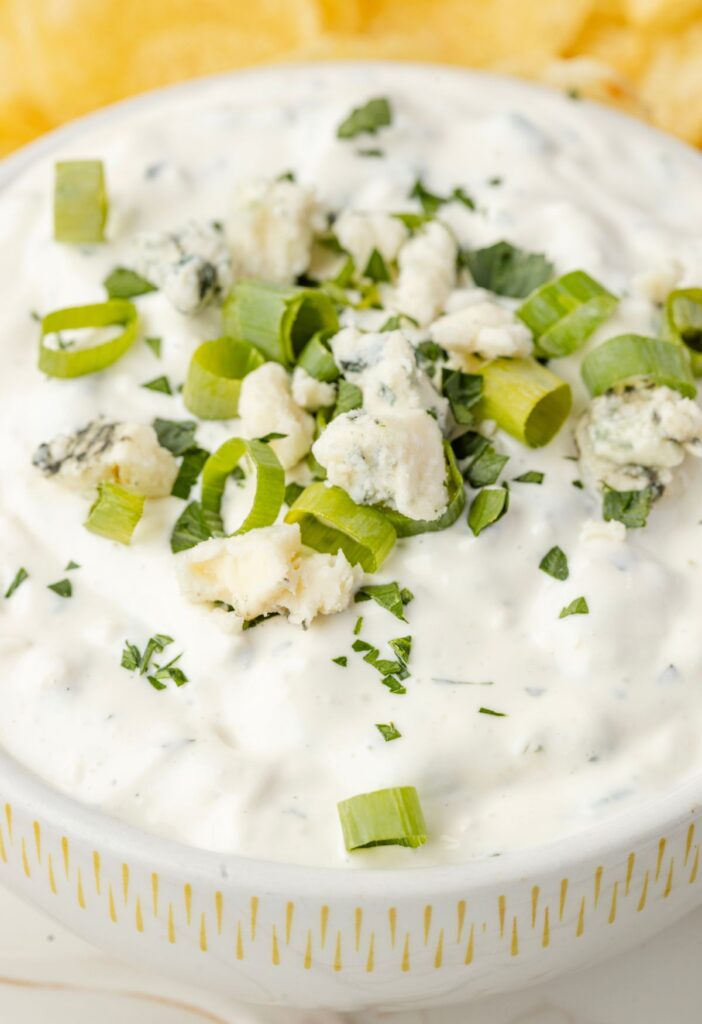 A bowl of blue cheese garnished with green onions and blue cheese crumbles