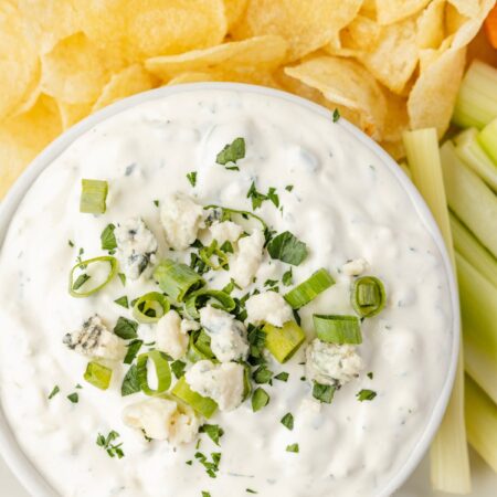 The blue cheese dip in a bowl on a platter with chips and carrots.
