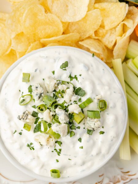 The blue cheese dip in a bowl on a platter with chips and carrots.