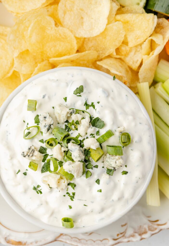 The blue cheese dip in a bowl on a platter with chips and carrots.