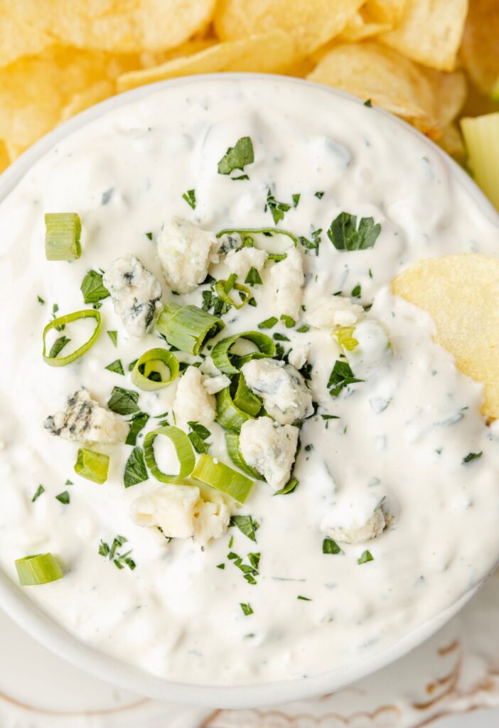 The dip with a potato chip being dipped into it.