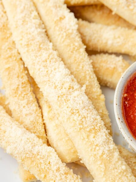 Crazy bread in a stack on a white serving plate.