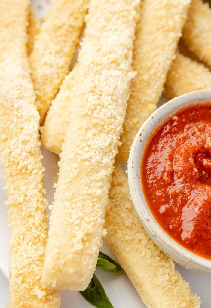 Breadsticks on a plate with parmesan cheese on top.