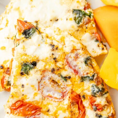 Egg white frittata on a white plate with fresh fruit to the side.