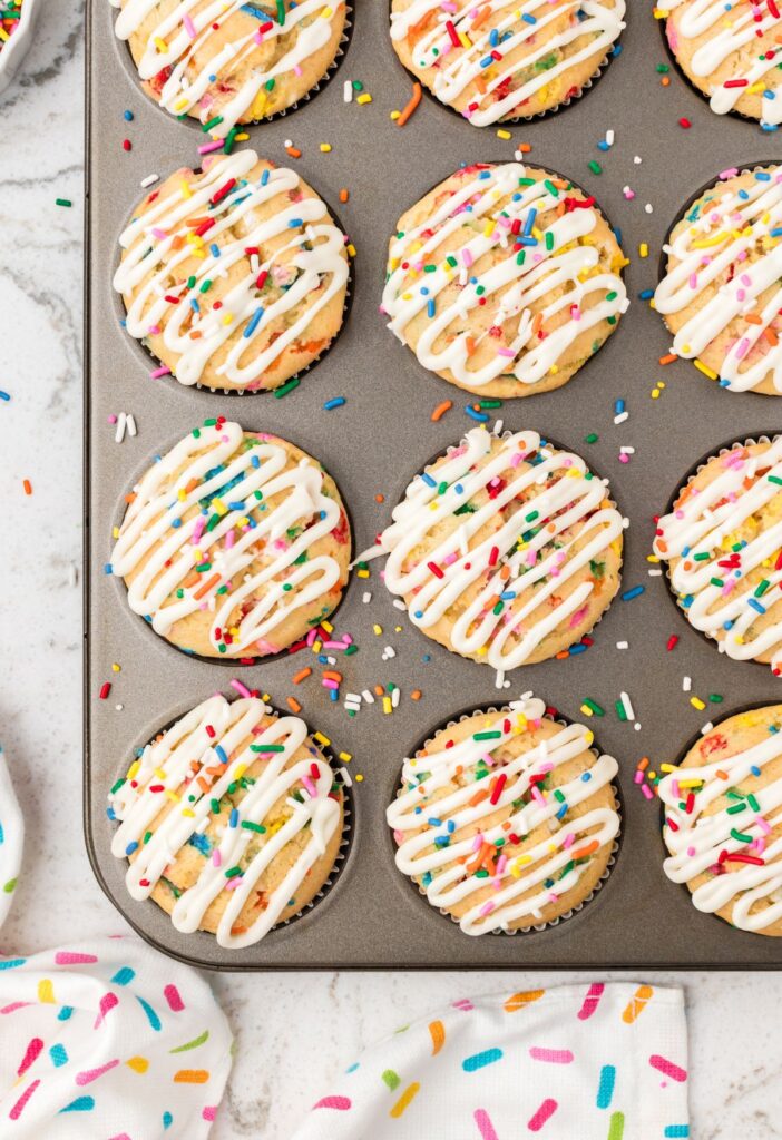 Muffin pan with funfetti muffins that have glaze them